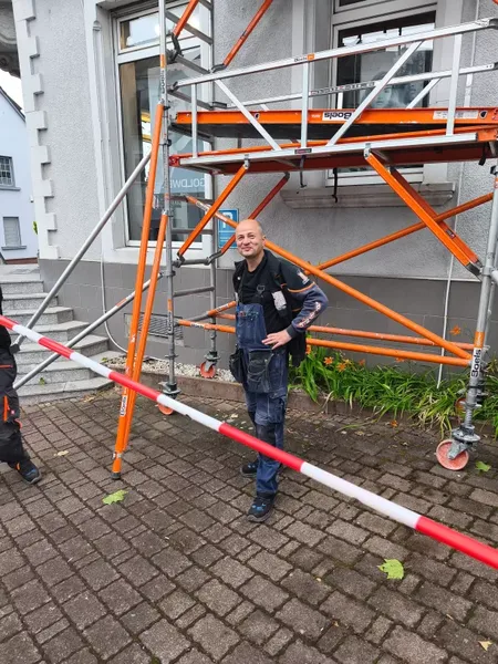 Monteur neben einem Gerüst bei Fassadenarbeiten