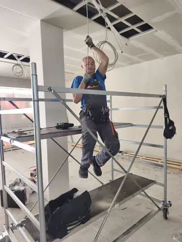Mitarbeiter von OK Bau UG bei Arbeiten an Leitungen unter einer geöffneten Decke.