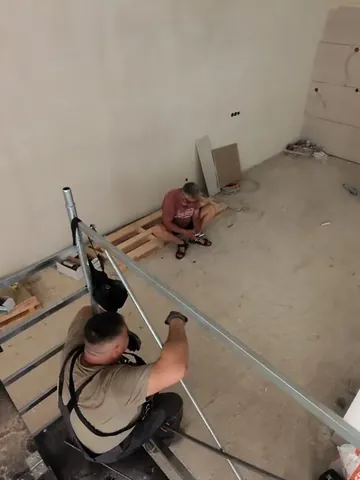 Mitarbeiter von OK Bau UG bei Rohrleitungsarbeiten auf dem Boden eines Rohbaus.
