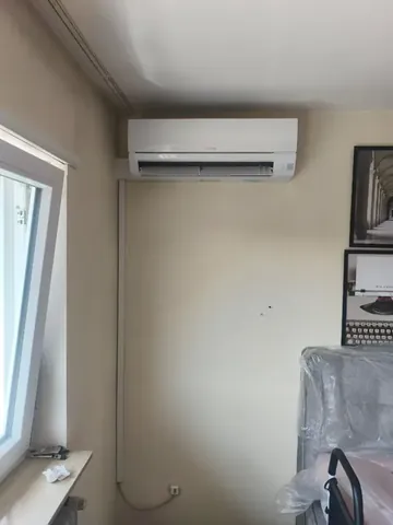 Wand-Innengerät einer Klimaanlage in einem Zimmer mit Dachschräge.